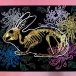 A golden bunny skeleton rests inside a burrow of chrysanthemums