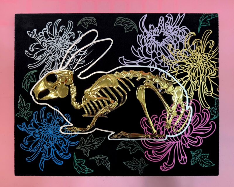 A golden bunny skeleton rests inside a burrow of chrysanthemums