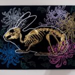 A golden bunny skeleton rests inside a burrow of chrysanthemums