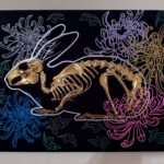 A golden bunny skeleton rests inside a burrow of chrysanthemums