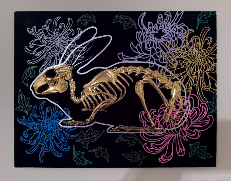 A golden bunny skeleton rests inside a burrow of chrysanthemums
