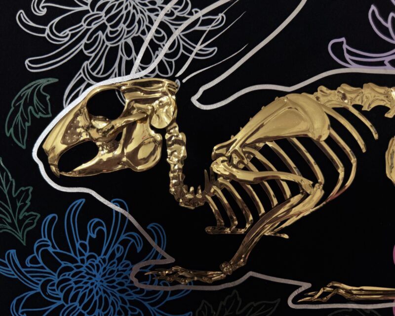 A golden bunny skeleton rests inside a burrow of chrysanthemums