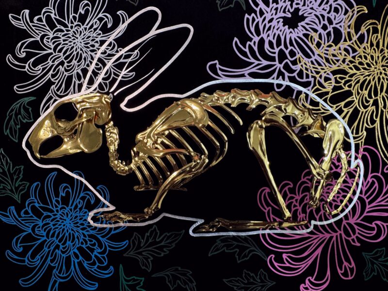 A golden bunny skeleton rests inside a burrow of chrysanthemums
