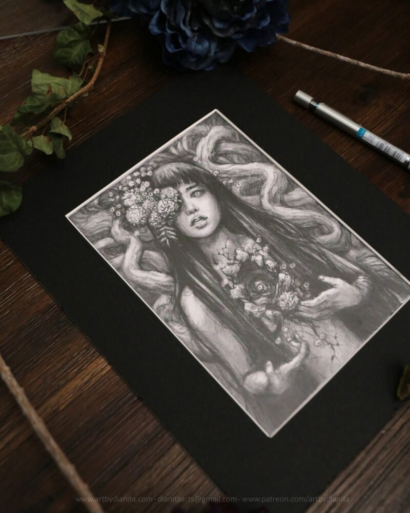 Graphite drawing of a female representing figure with marigolds coming out of one of her eyes. Long dark hair. Chest open, edges look like bark. A marigold comes out of the space. Tree branches at her back.