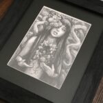 Graphite drawing of a female representing figure with marigolds coming out of one of her eyes. Long dark hair. Chest open, edges look like bark. A marigold comes out of the space. Tree branches at her back.