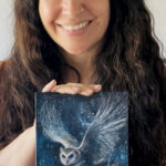 Mary Ancilla Martinez holding her original acrylic painting Night Messenger, a mystical owl in flight.