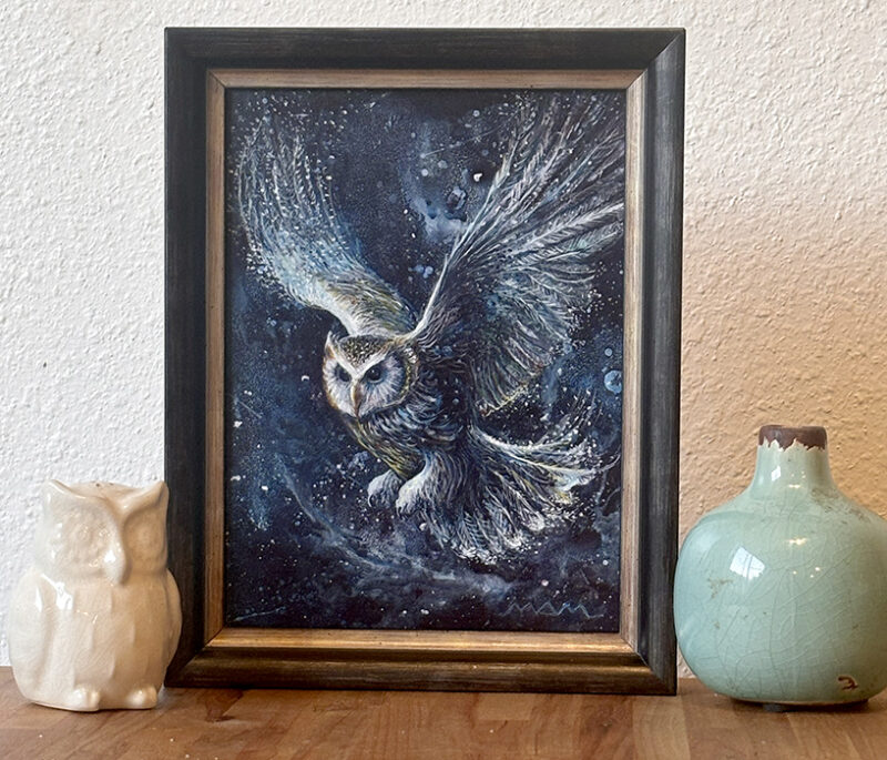 Night Messenger, a framed mystical owl painting displayed on a table, showing the artwork in a home setting.