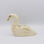 A ceramic swan sculpture with sgraffito details done with white clay and gold luster details such as a golden beak, a constellation that runs on the side of it's chest, and floral details on the wings. This side shows a golden eye.