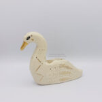 A ceramic swan sculpture with sgraffito details done with white clay and gold luster details such as a golden beak, a constellation that runs on the side of it's chest, and floral details on the wings. This side shows a golden eye.